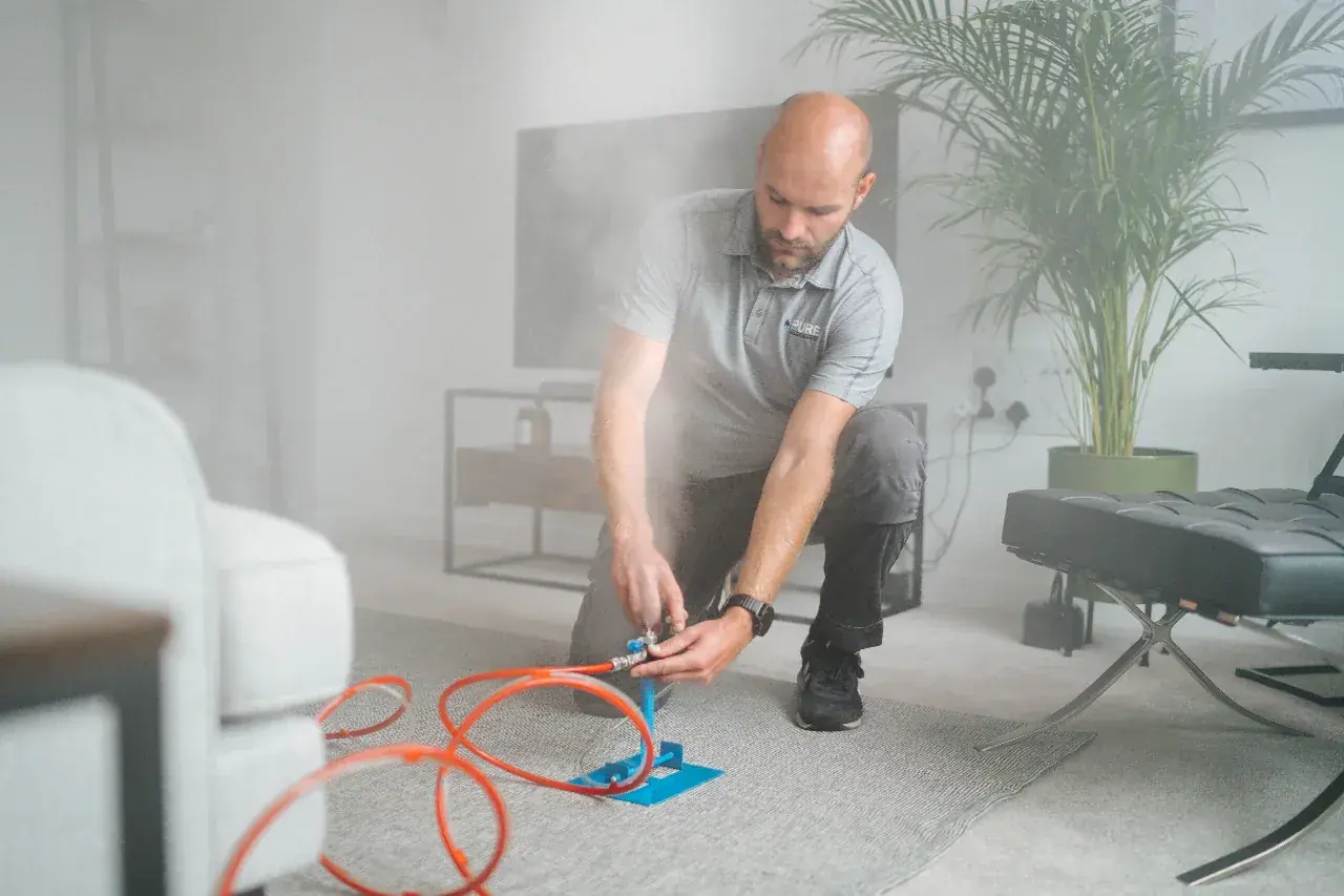 A technician sets up a dry fog head in a living room